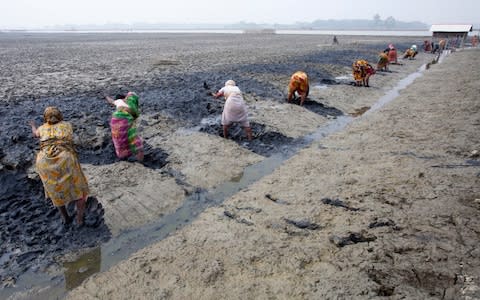 Women clear wet mud alongside the bank of the river in Satkhira, Bangladesh. Bangladesh is one of the continental countries most vulnerable to climate change. - Credit: Zakir/Hossain Chowdhury/Barcroft 
