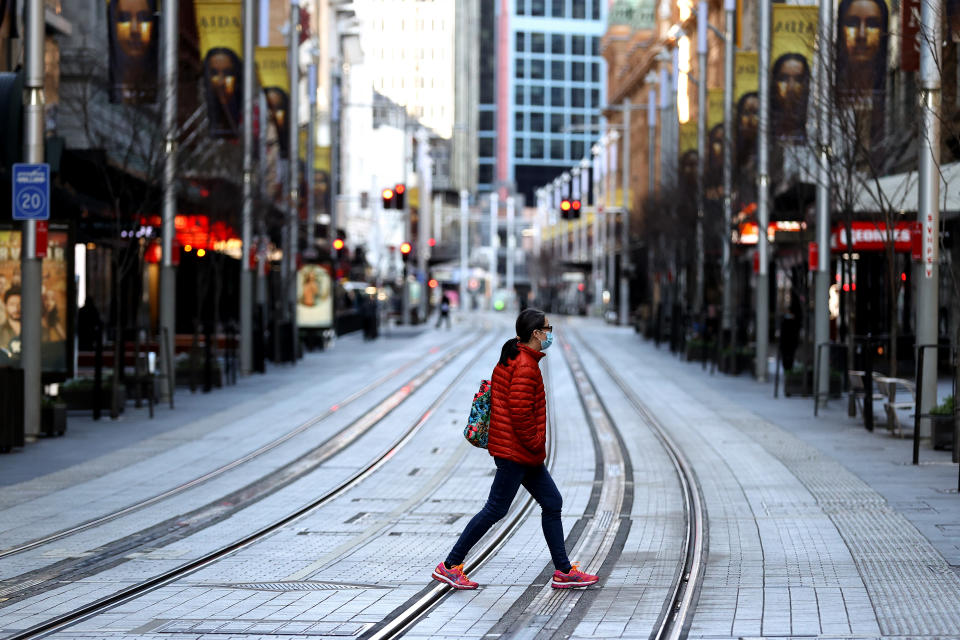A woman in a red coat crosses George Street in Sydney's CBD.