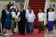 YANGON, MYANMAR - NOVEMBER 19: US President Barack Obama alongside Secretary of State Hilary Clinton (6th-R) and Burmese Foreign minister Wunna Maung Lwin (3rd-R) are greeted with flowers as they arrive at Yangon International airport during a historical visit to the country on November 19, 2012 in Yangon, Myanmar. Obama is the first US President to visit Myanmar while on a four-day tour of Southeast Asia that also includes Thailand and Cambodia. (Photo by Paula Bronstein/Getty Images)