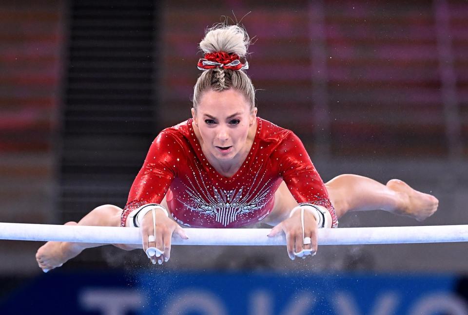 Mykayla Skinner is suspended parallel to the ground as she grasps one of the uneven bars.