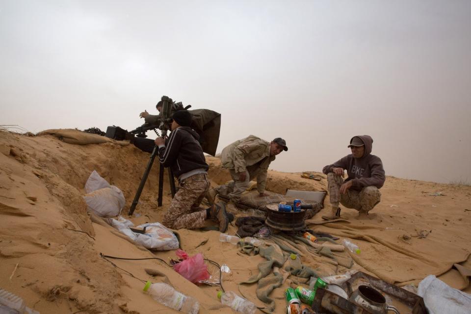 FILE - In this Saturday, Feb. 21, 2015 file photo, Libyan soldiers aim their weapons during clashes with militants on the frontline in Al Ajaylat, 120 kilometers (75 miles) west of Tripoli, Libya. The United Nations said Friday, Oct. 23, 2020, that the two sides in Libyan military talks had reached a "historic achievement" with a permanent cease-fire agreement across the war-torn North African country. (AP Photo/Mohamed Ben Khalifa, File)