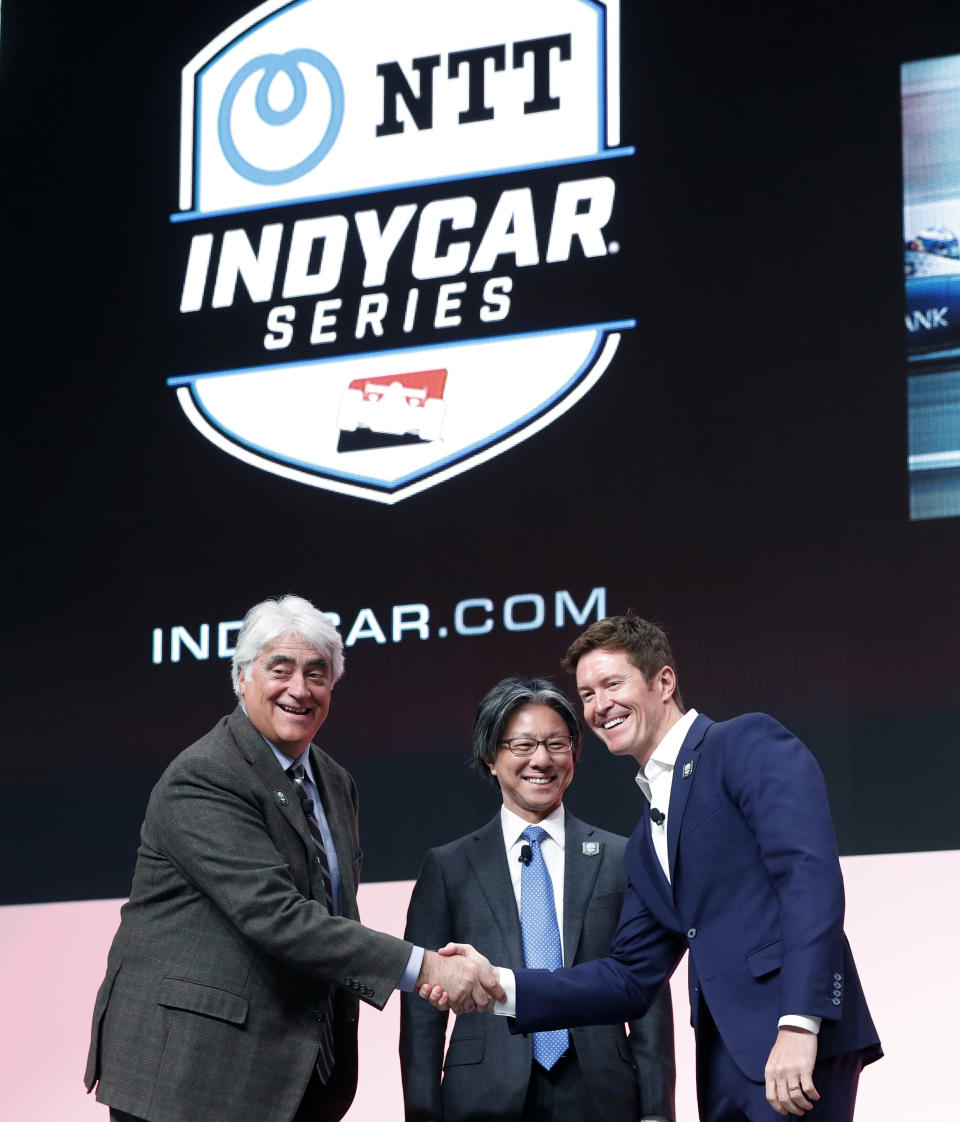 FILE - In this Jan. 15, 2019, file photo, from left, IndyCar CEO Mark Miles, Tsuneshia Okuno, an executive vice president at NTT and 2018 series champion Scott Dixon shake hands during a news conference at the North American International Auto Show in Detroit. Deals done since Scott Dixon wrapped up his fifth IndyCar championship last September include new title sponsorship from Japanese communications giant NTT, the transition to a single steady television partner in NBC Sports and a push toward expanding the grid that has made it easier for new teams to crack into the series. (AP Photo/Carlos Osorio, File)
