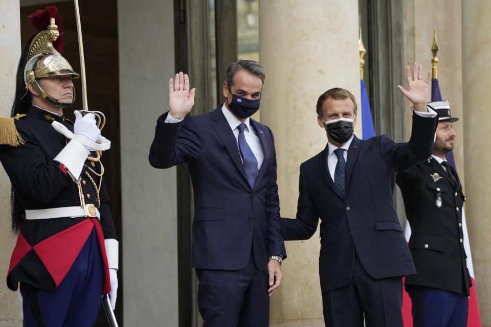 French President Emmanuel Macron and Prime Minister Kyriakos Mitsotakis, center, wave Tuesday, Sept. 28, 2021 at the Elysee Palace in Paris. The leaders of Greece and France are expected to announce a major, multibillion-euro deal in Paris on Tuesday involving the acquisition by Greece of at least six French-built warships, Greek state ERT TV reported. (AP Photo/Francois Mori)