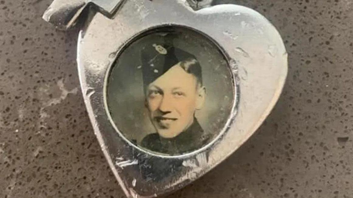 Silver heart-shaped fob containing a round photograph of a young man in military uniform