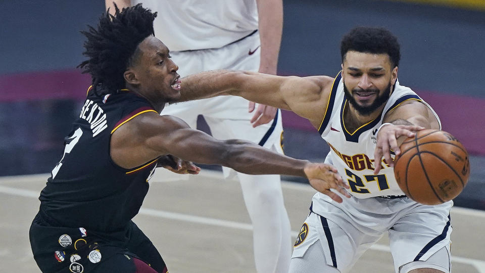 Cleveland Cavaliers' Collin Sexton, left, and Denver Nuggets' Jamal Murray reach for the ball during the first half of an NBA basketball game Friday, Feb. 19, 2021, in Cleveland. (AP Photo/Tony Dejak)