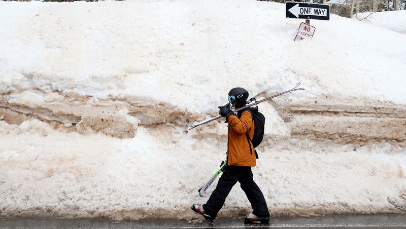 Ankur Patel walks beside a large snowbank in Brighton on March 13. Brighton Resort surpassed 700 inches of snow this season by Monday, marking the earliest a resort has received at least 700 inches in 80 years of record-keeping.