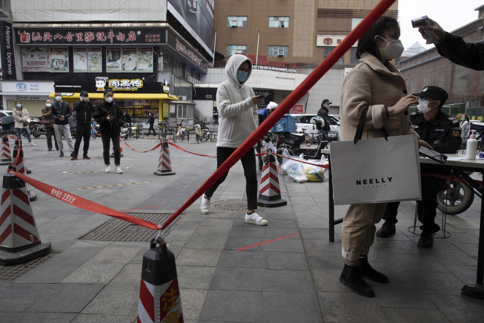 Residents wearing masks to protect against the spread of the coronavirus line up to enter a supermarket in Wuhan in central China's Hubei province on Friday, April 3, 2020. Chinese leaders are trying to revive the economy, but local officials under orders to prevent new infections are enforcing disease checks and other controls that add to financial losses and aggravation for millions of workers. (AP Photo/Ng Han Guan)