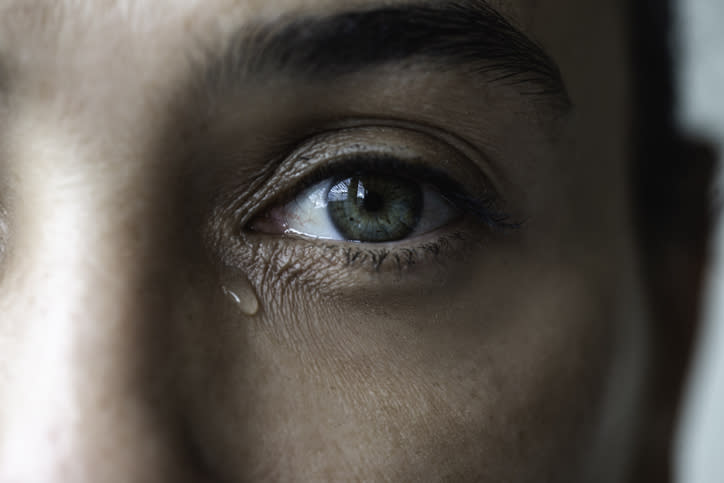 Close-up of a person's eye with a single tear running down their cheek