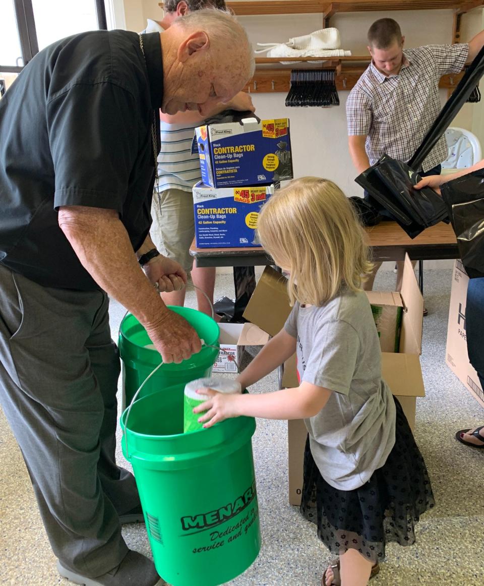 Pastor Jerry Rhea, left, and Kaylee Hottel, work to stock the green buckets while Josh Hottel works at the table at Jeromesville Lutheran Church as volunteer packed essentials to be sent to Iowa for disaster relief.