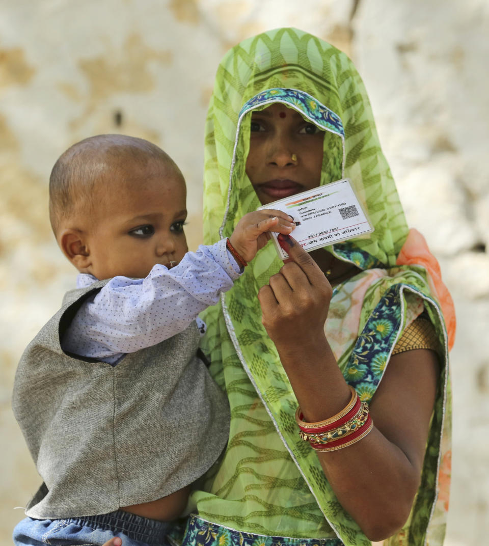 An Indian woman displays her voters identity card after casting her vote in Chayal village, in Kausambi district of Uttar Pradesh state, India, Monday, May 6, 2019. Voting began amid scorching summer temperatures and tight security in Uttar Pradesh in northern India, where more than 25 million people are registered to cast ballots for 14 members of India's Parliament. (AP Photo/Rajesh Kumar Singh)