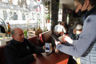 A waiter checks a man's vaccine pass, at a restaurant in Lille, northern France, Monday, Jan. 24, 2022. Unvaccinated people are no longer allowed in France's restaurants, bars, tourist sites and sports venues, as a new law came into effect Monday requiring a "vaccine pass" that is central to the government's anti-virus strategy. (AP Photo/Michel Spingler)