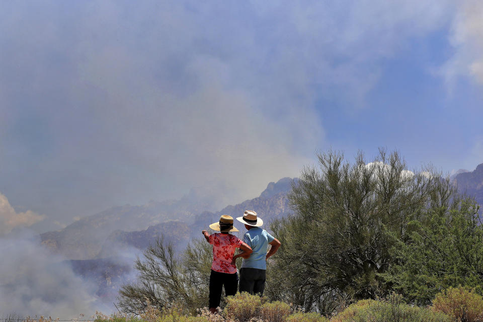 A couple watches the Bighorn Fire burn along the northwestern side of the Santa Catalina Mountains, Friday, June 12, 2020, in Oro Valley, Ariz. Hundreds of homes on the outskirts of Tucson remain under an evacuation notice as firefighters work to keep the wildfire from moving downhill from canyons and ridges in the Coronado National Forest. (AP Photo/Matt York)