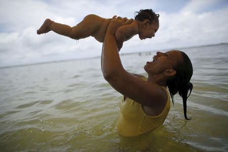 Rosana Vieira Alves holds her 4-month-old daughter Luana Vieira, who was born with microcephaly, in the sea in Olinda, Brazil, February 4, 2016. REUTERS/Ueslei Marcelino