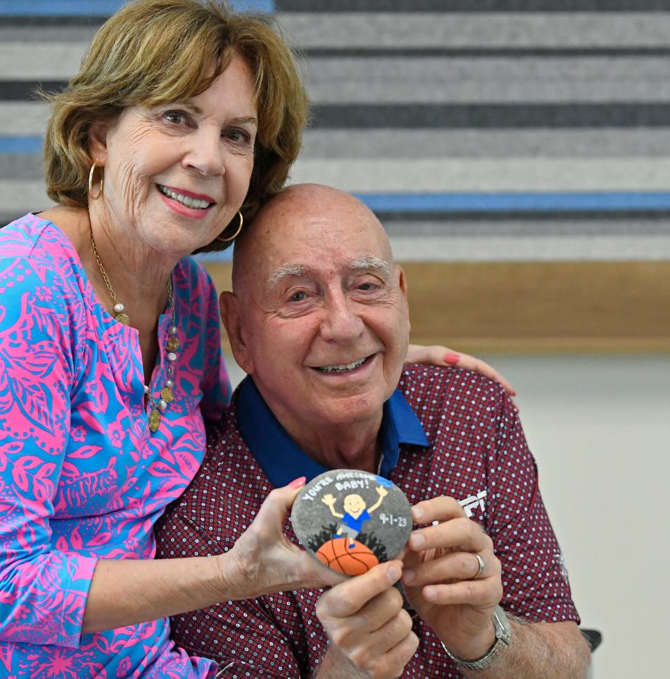 Dick and Lorraine Vitale display the rock given to the Lakewood Ranch resident and ESPN college basketball announcer by the staff of the Sarasota Memorial Radiation Oncology Center after the 84-year-old completed last month his 35th and final radiation treatment for vocal cord cancer. Vitale announced that his return to the microphone for his 45th season calling games for ESPN will have to be delayed as his voice needs further healing. VItale planned to return for the Nov. 28 game between Kentucky and Miami.