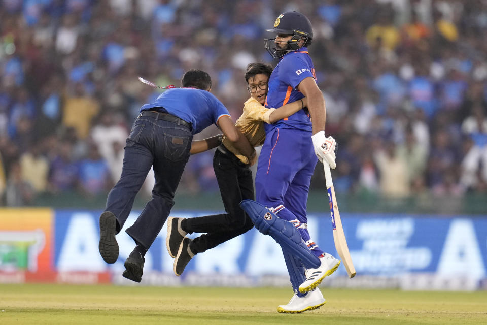 A security guard tries to separate a boy who hugs India's captain Rohit Sharma, right, after invading the field of play during the second one-day international cricket match between India and New Zealand in Raipur, India, Saturday, Jan. 21, 2023. (AP Photo/Aijaz Rahi)