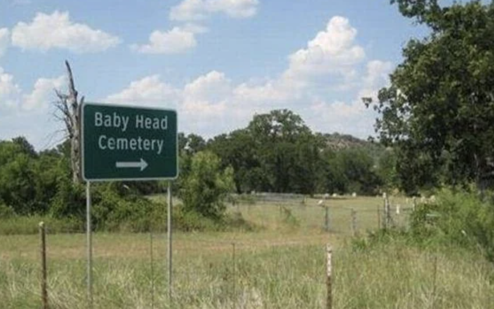 Sign pointing to "Baby Head Cemetery" next to a rural landscape