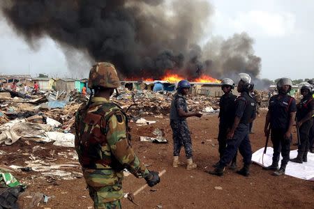 Security forces watch as residents burn dwellings in an impoverished neighborhood in Accra, Ghana, June 20, 2015. REUTERS/Staff