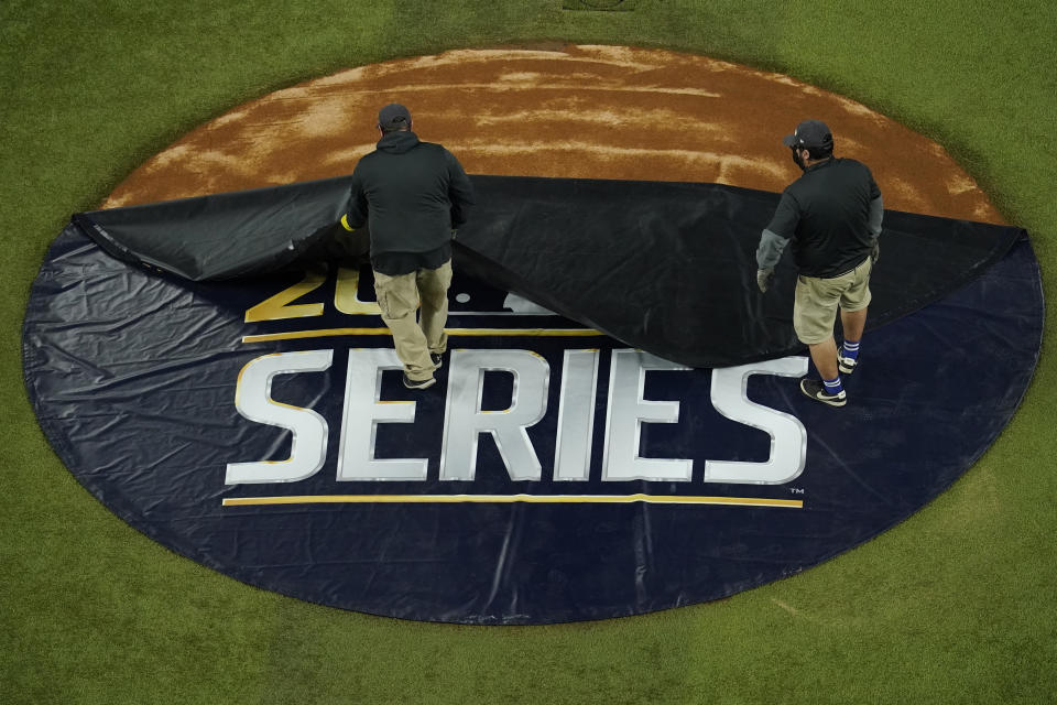 Members of the grounds crew uncover the pitcher's mound before Game 3 of the baseball World Series between the Los Angeles Dodgers and the Tampa Bay Rays Friday, Oct. 23, 2020, in Arlington, Texas. (AP Photo/David J. Phillip)