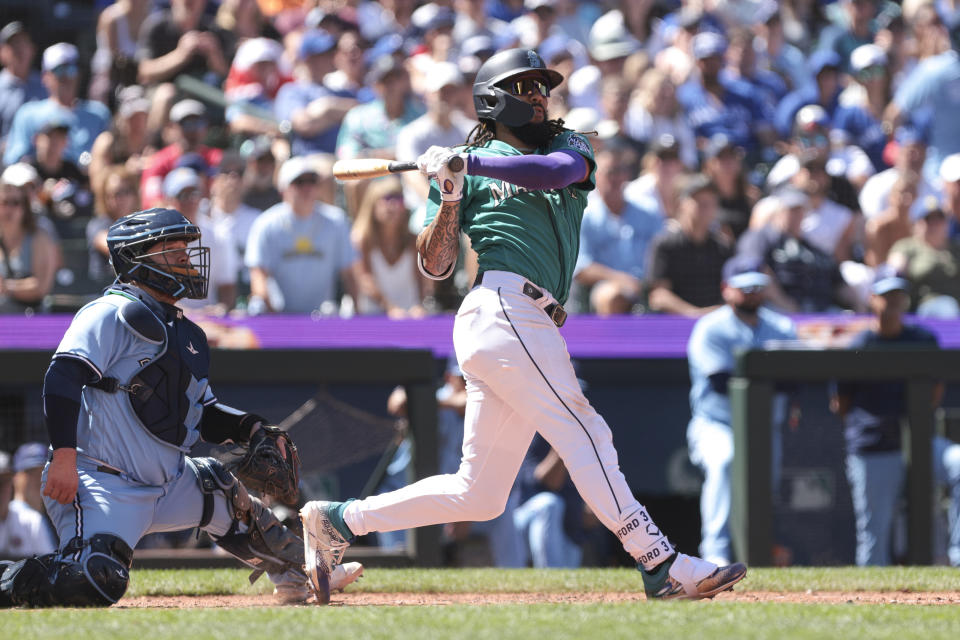 Seattle Mariners' J.P. Crawford, right, follows through on a two-run double as Toronto Blue Jays catcher Alejandro Kirk, left, looks on during the seventh inning of a baseball game, Saturday, July 22, 2023, in Seattle. (AP Photo/Jason Redmond)