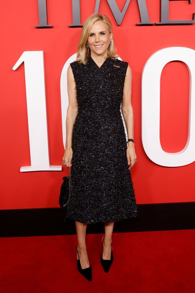 Tory Burch standing on the TIME 100 red carpet in a sleeveless, mid-length textured dress and black heels