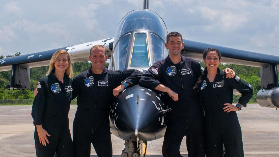     Vier Menschen in dunklen Anzügen lehnen sich an einen Jet. 