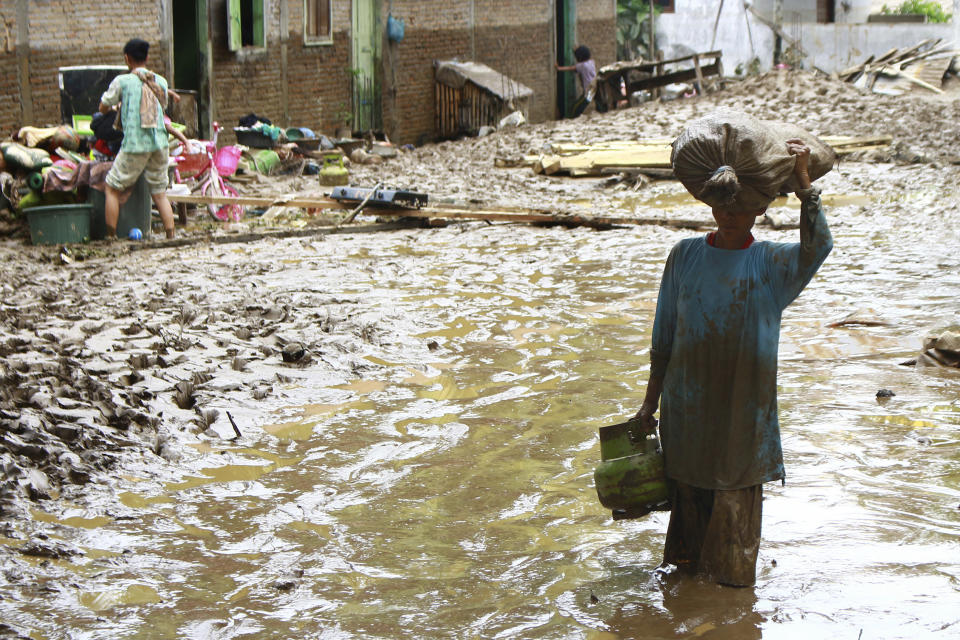 A resident walks through mud in Central Tapanuli, North Sumatra, Indonesia Wednesday, Jan. 29, 2020. Landslides and floods from torrential rains in Indonesia' Sumatra island leave a scores of people dead and displaced thousands, the country's disaster agency said Wednesday. (AP Photo/Damai Mendrofa)