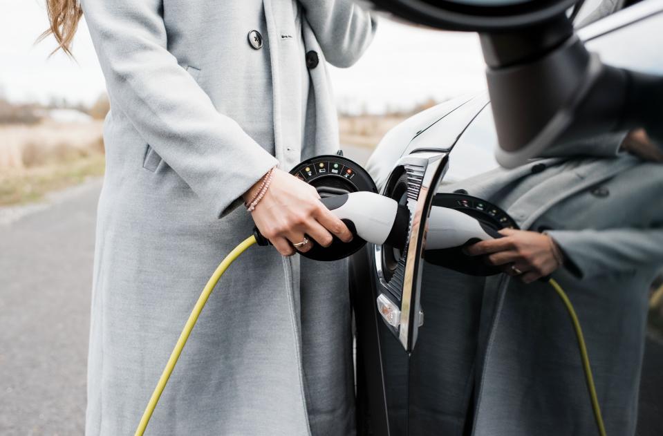 Una mujer carga un vehículo eléctrico (Getty Creative). 