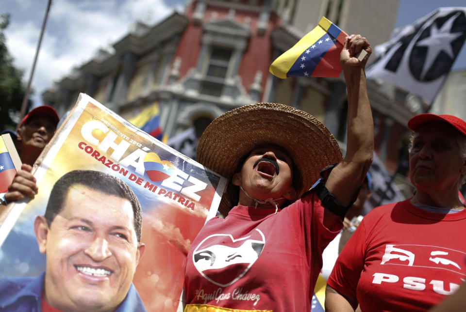 A government supporter holding an image of late Venezuelan President Hugo Chavez cheers during a rally on the sidelines of the Sao Paulo Forum in Caracas, Venezuela, Saturday, July 27, 2019. The Sao Paulo forum, held almost annually and hosted by Cuba last year, was founded as Latin American leftists sought to re-organize after the fall of the Berlin Wall in 1989. (AP Photo/Leonardo Fernandez)