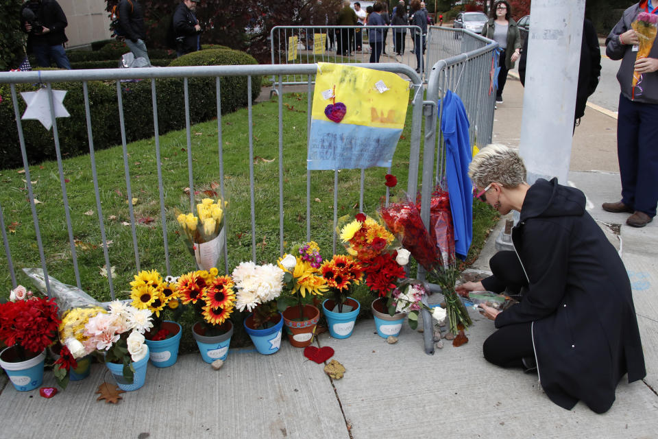 A woman places stones along a fence outside the Tree of Life synagogue in Pittsburgh on Sunday, Oct. 27, 2019, the first anniversary of the shooting at the synagogue, that killed 11 worshippers.(AP Photo/Gene J. Puskar)