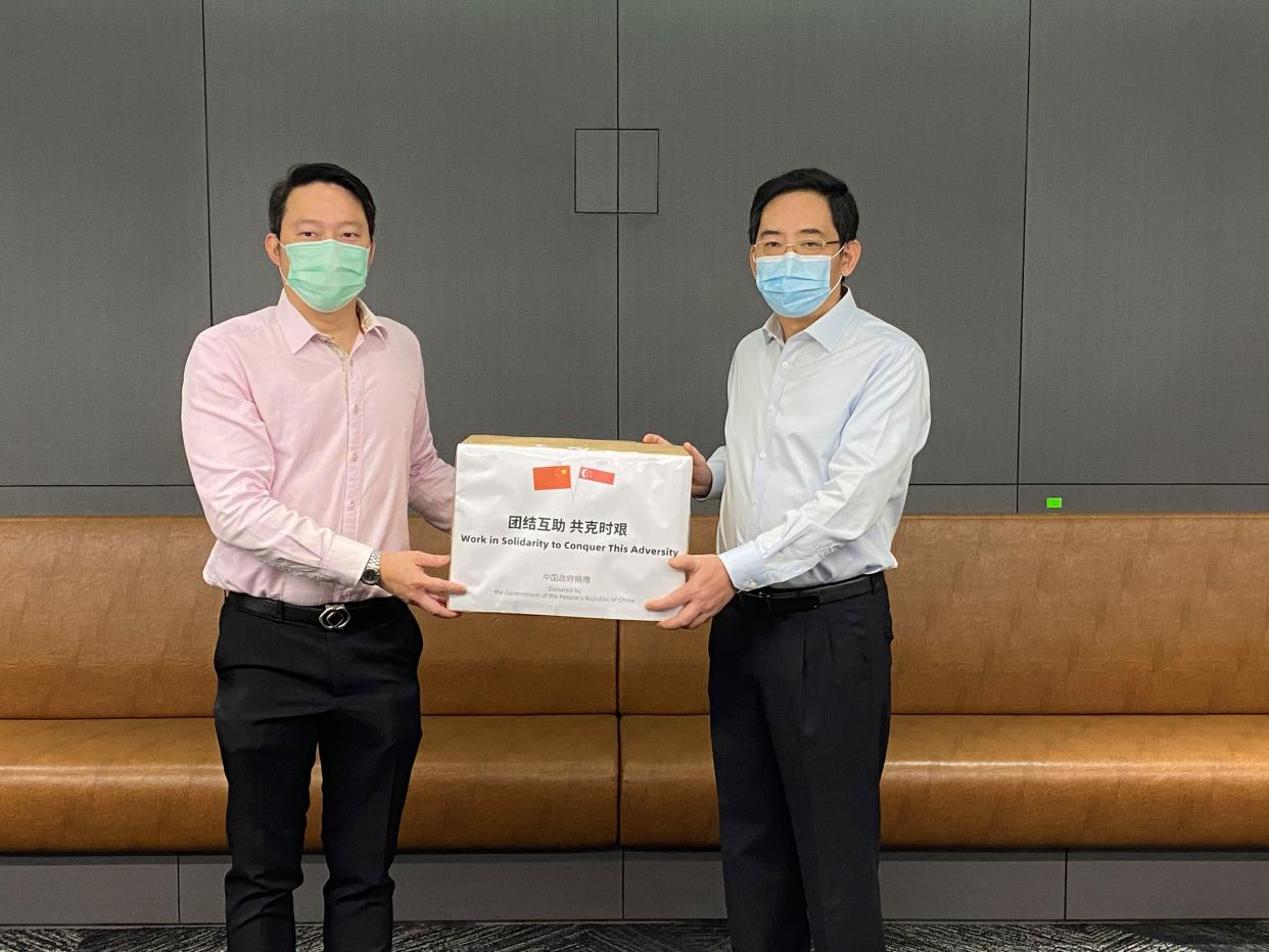 Senior Minister of State for Health and Transport Lam Pin Min (left) receives a donation of face masks from China ambassador Hong Xiaoyong. (PHOTO: Ministry of Health)