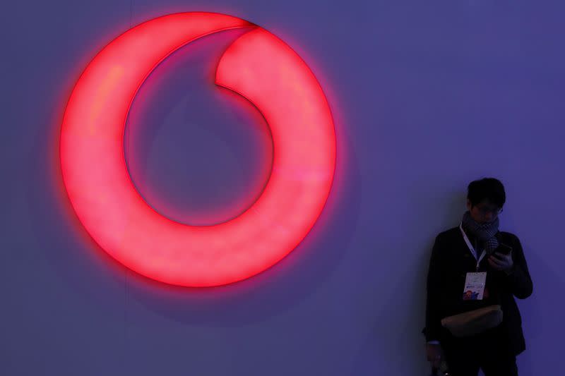 A man checks his mobile phone next to a Vodafone logo at the Mobile World Congress in Barcelona