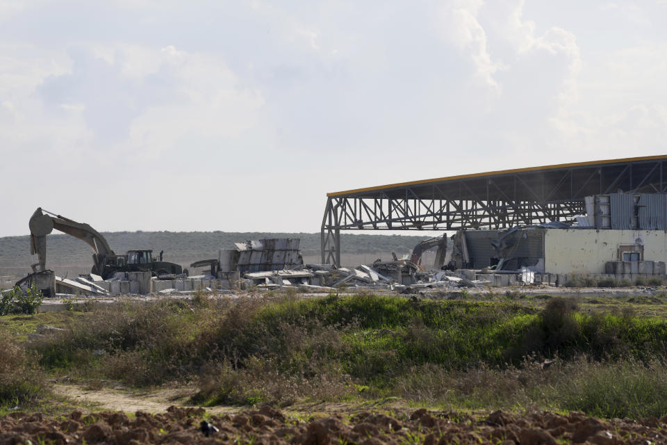 Israeli excavator and cranes demolish the remains of Karni commercial border crossing between Israel and Gaza Strip, east of Gaza City, Tuesday, Dec. 6, 2022. Israeli bulldozers and cranes were seen Tuesday dismantling a commercial crossing point on the eastern side of Gaza City as Israel decided to extend a security barrier at the location of the long-defunct terminal. (AP Photo/Adel Hana)