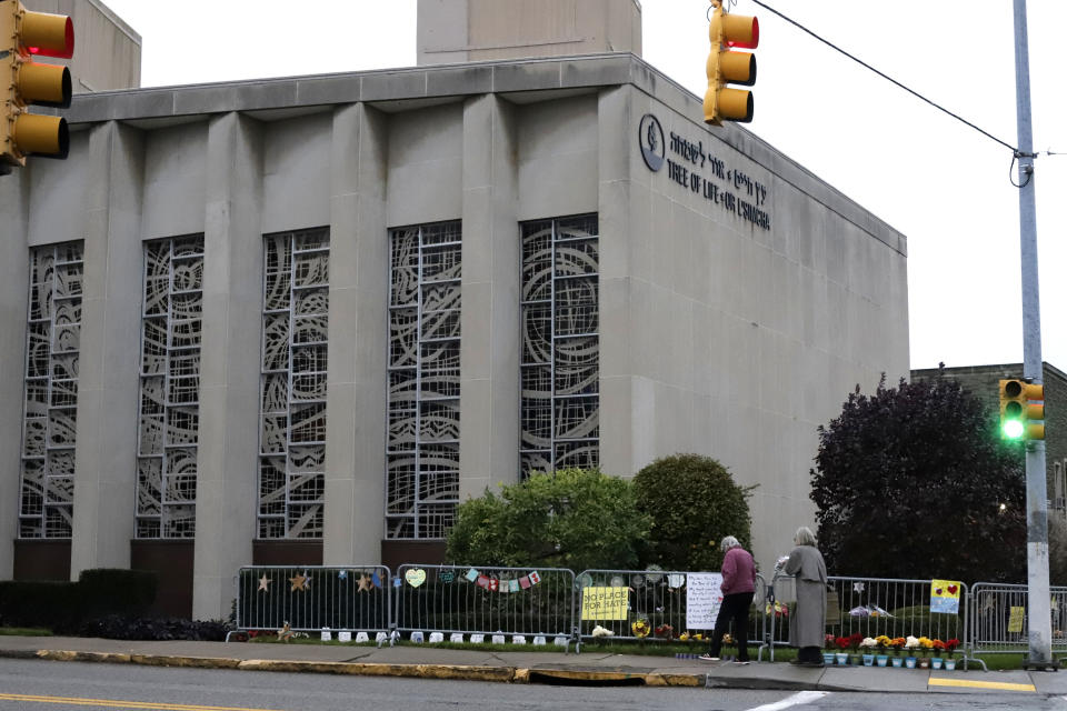 People pause in front of mementos placed along a fence surrounding the Tree of Life synagogue in Pittsburgh, on Saturday, Oct. 26, 2019. The first anniversary of the shooting at the synagogue that killed 11 worshippers and injured others is on Sunday, Oct., 27, 2019. (AP Photo/Gene J. Puskar)