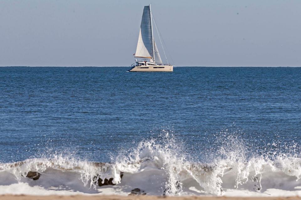 A sail boat in the horizon and waves are featured in Rehoboth Beach, Tuesday, Dec. 12, 2023.