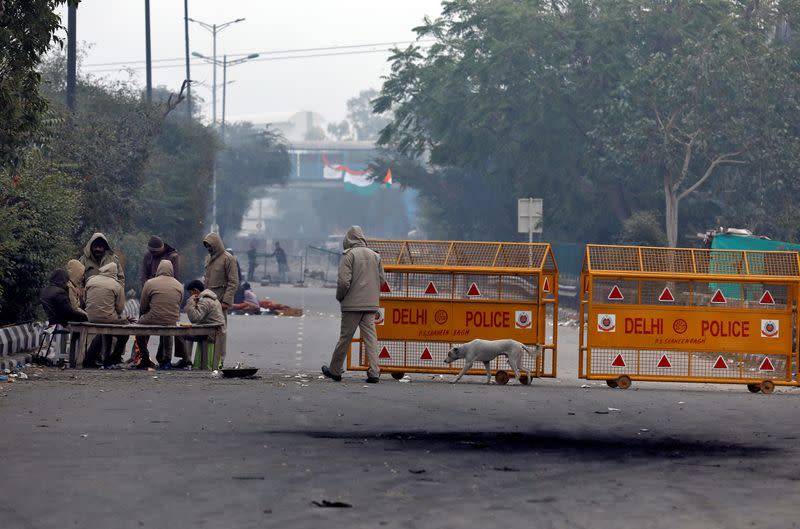 Police officers sit around a bonfire to keep themselves warm next to a barricade during a protest against a new citizenship law, in New Delhi