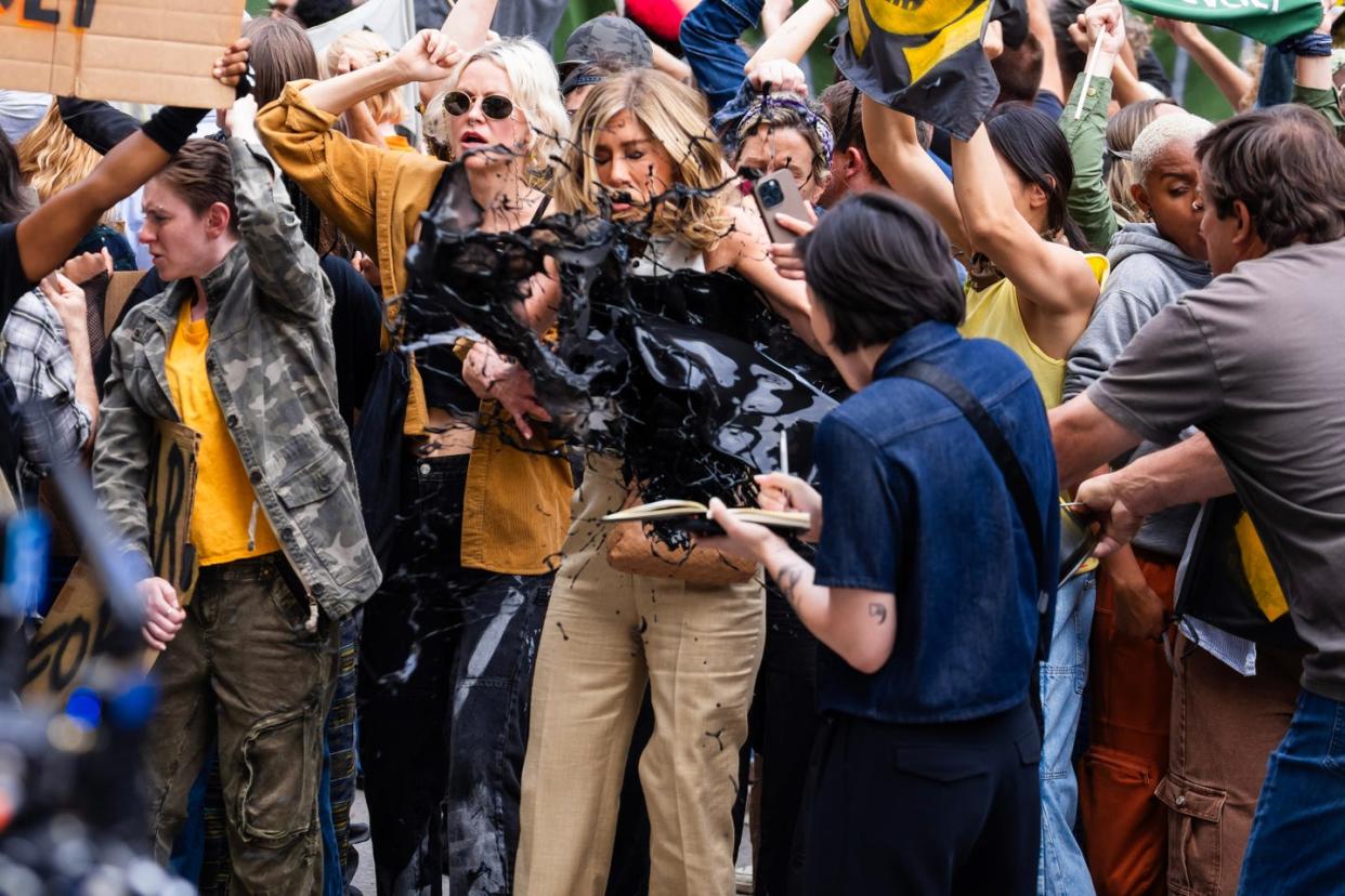 jennifer aniston is covered in oil by a man in a grey tshirt while filming a scene for the morning show