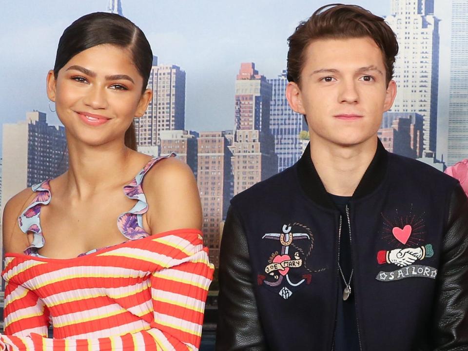 Zendaya, Tom Holland, and Laura Harrier sitting on a bench together while promoting "Spider-Man: Homecoming."