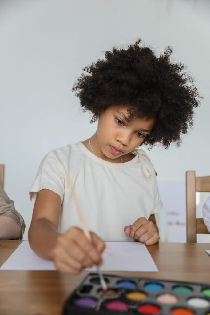 Little black girl painting with watercolors