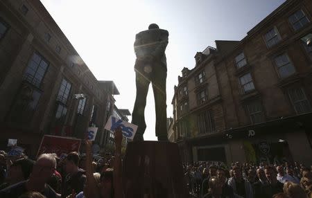 Supporters of the "Yes" campaign hold up posters as they try to disrupt a "No" campaign rally that Labour party leader Ed Miliband addressed, close to a statue of Donald Dewar who was the first First Minister of Scotland, in Glasgow, September 11, 2014.REUTERS/Paul Hackett