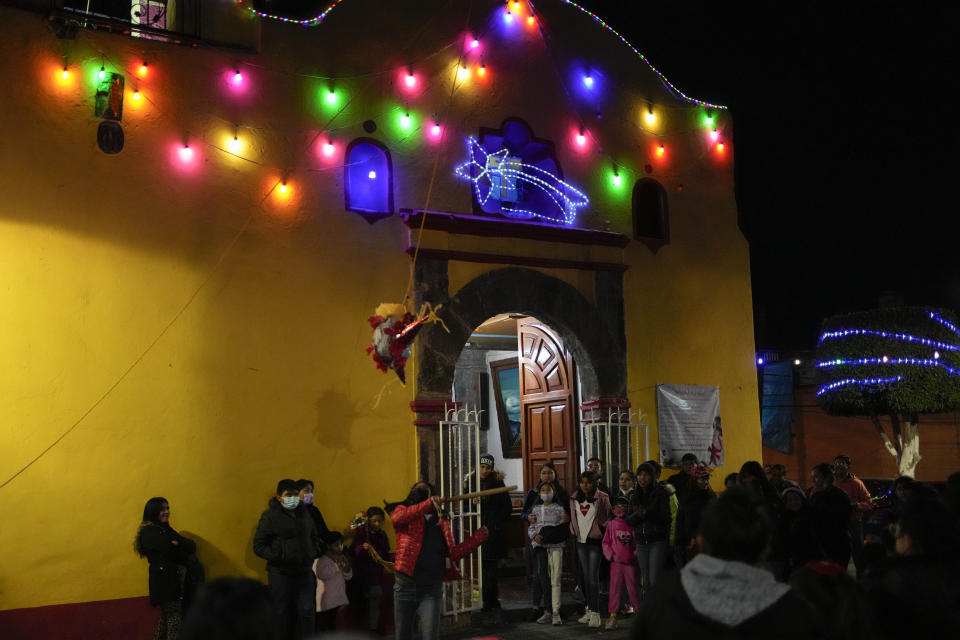 A woman hits a traditional Christmas "pinata" filled with fruit and candy during a Christmas "posada," which means lodging or shelter, in the Xochimilco borough of Mexico City, Wednesday, Dec. 21, 2022. For the past 400 years, residents have held posadas between Dec. 16 and 24, when they take statues of baby Jesus in procession to church for Mass to commemorate Mary and Joseph's cold and difficult journey from Nazareth to Bethlehem in search of shelter. (AP Photo/Eduardo Verdugo)