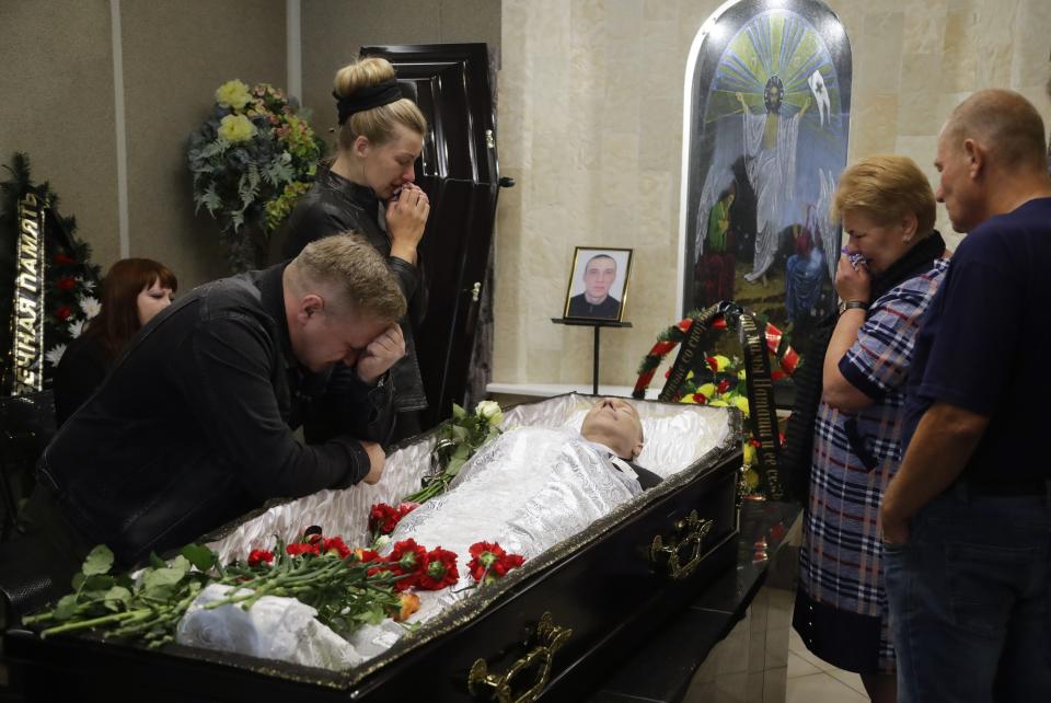 Elena German, life partner of Alexander Taraikovsky who died amid the clashes protesting the election results, and his relatives mourn during his funeral in Minsk, Belarus, Saturday, Aug. 15, 2020. Taraikovsky died Monday as demonstrators roiled the streets of the capital Minsk, denouncing official figures showing that authoritarian President Alexander Lukashenko, in power since 1994, had won a sixth term in office. (AP Photo/Sergei Grits)