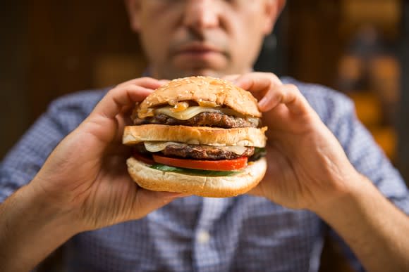 A man holding up a juicy burger