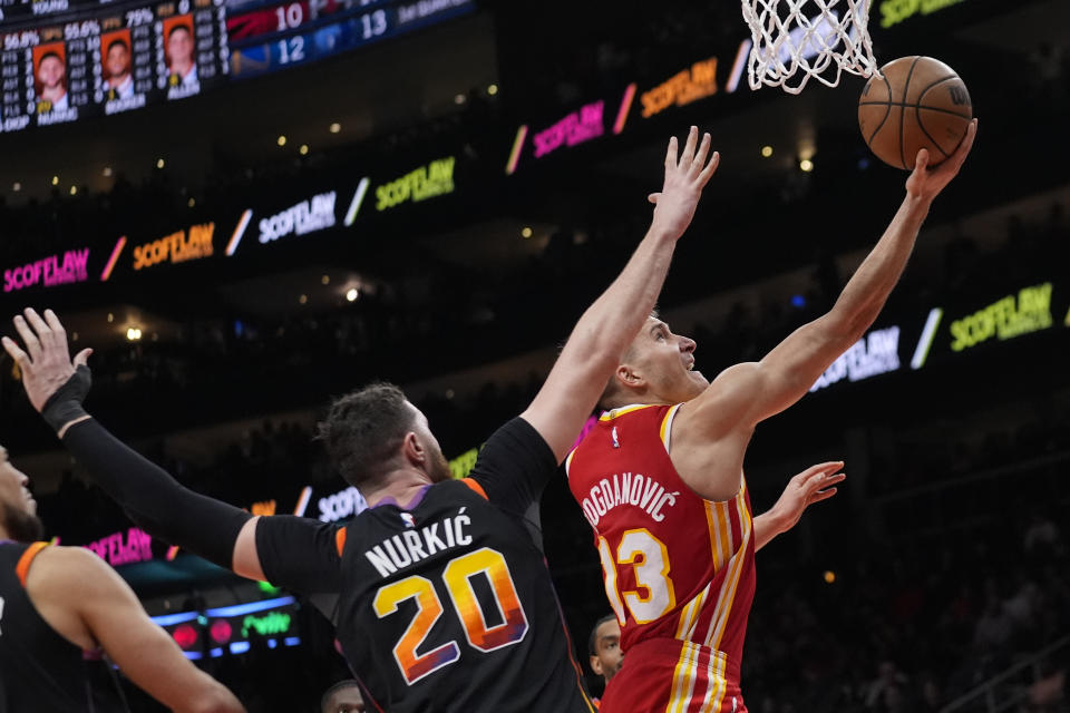 Atlanta Hawks guard Bogdan Bogdanovic (13) drives past Phoenix Suns center Jusuf Nurkic (20) as hscores a basket in the first half of an NBA basketball game Friday, Feb. 2, 2024, in Atlanta. (AP Photo/John Bazemore)