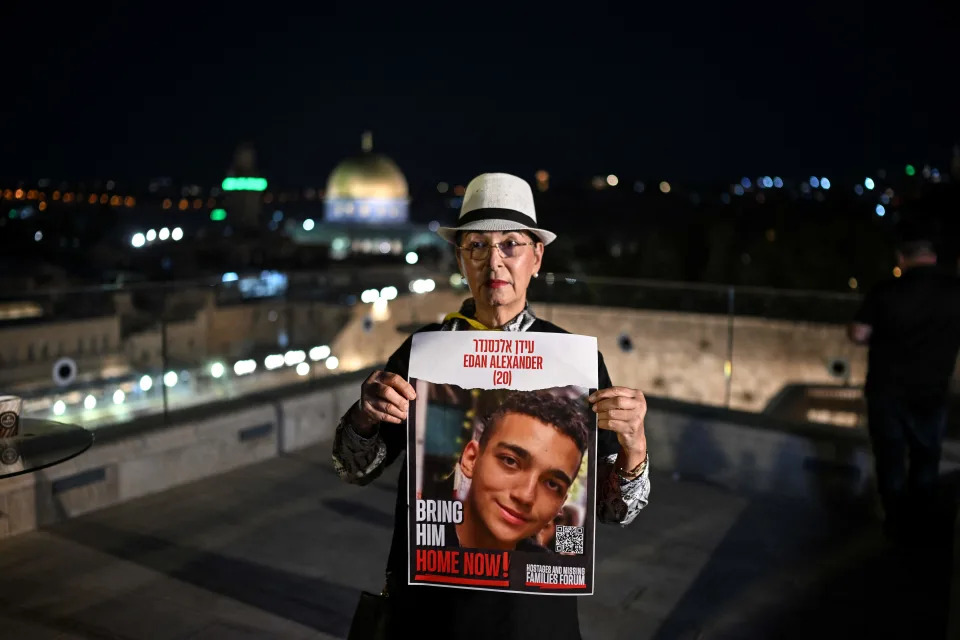 A woman holds an image of hostage Edan Alexander. 