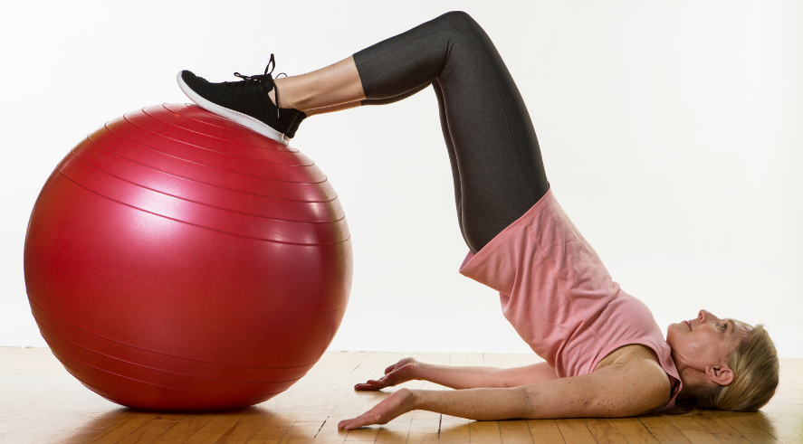 Girl on floor stretching with exercise ball.