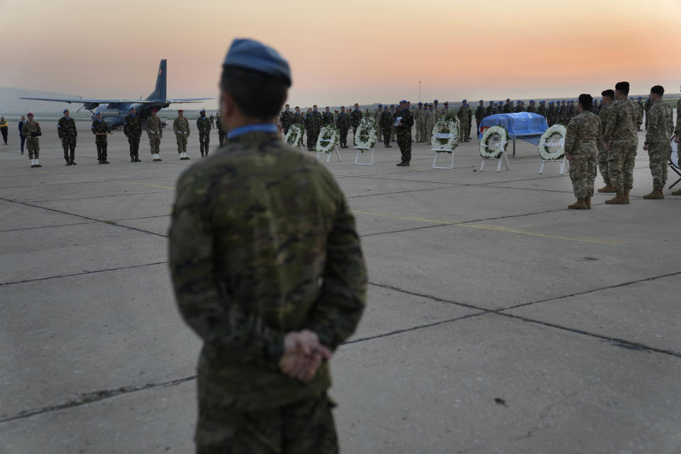 Lebanese soldiers, Irish and other nationalities U.N. peacekeepers, stand around the coffin draped by the United Nations flag of their comrade Pvt. Seán Rooney who was killed during a confrontation with residents near the southern town of Al-Aqbiya on Wednesday night, during his memorial procession at the Lebanese army airbase, at Beirut airport, Sunday, Dec. 18, 2022. (AP Photo/Hussein Malla)