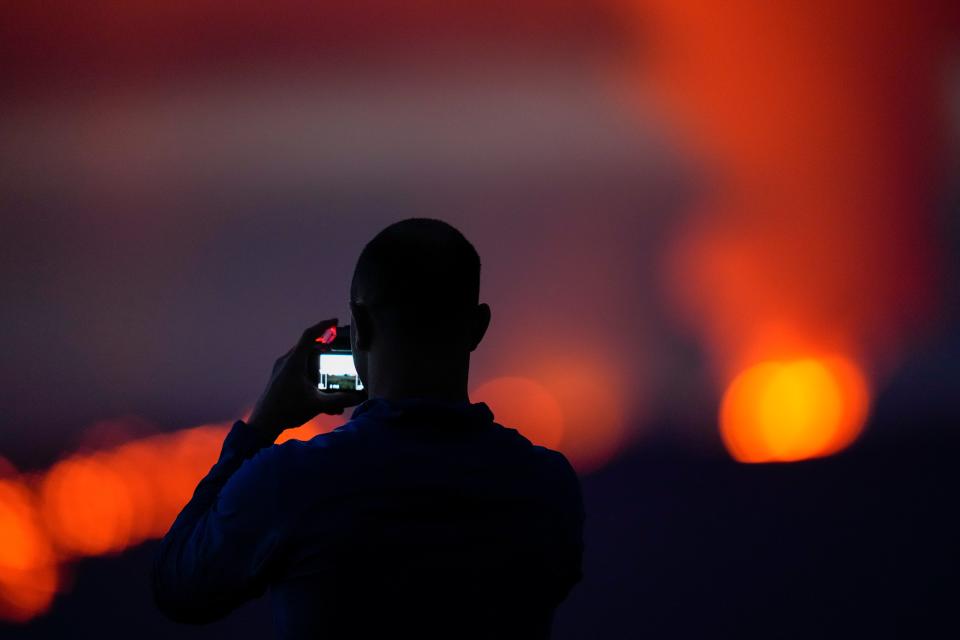 Brian Lichtenstein, of San Diego, takes a photo in front of lava erupting from Hawaii's Mauna Loa volcano Wednesday, Nov. 30, 2022, near Hilo, Hawaii (AP)