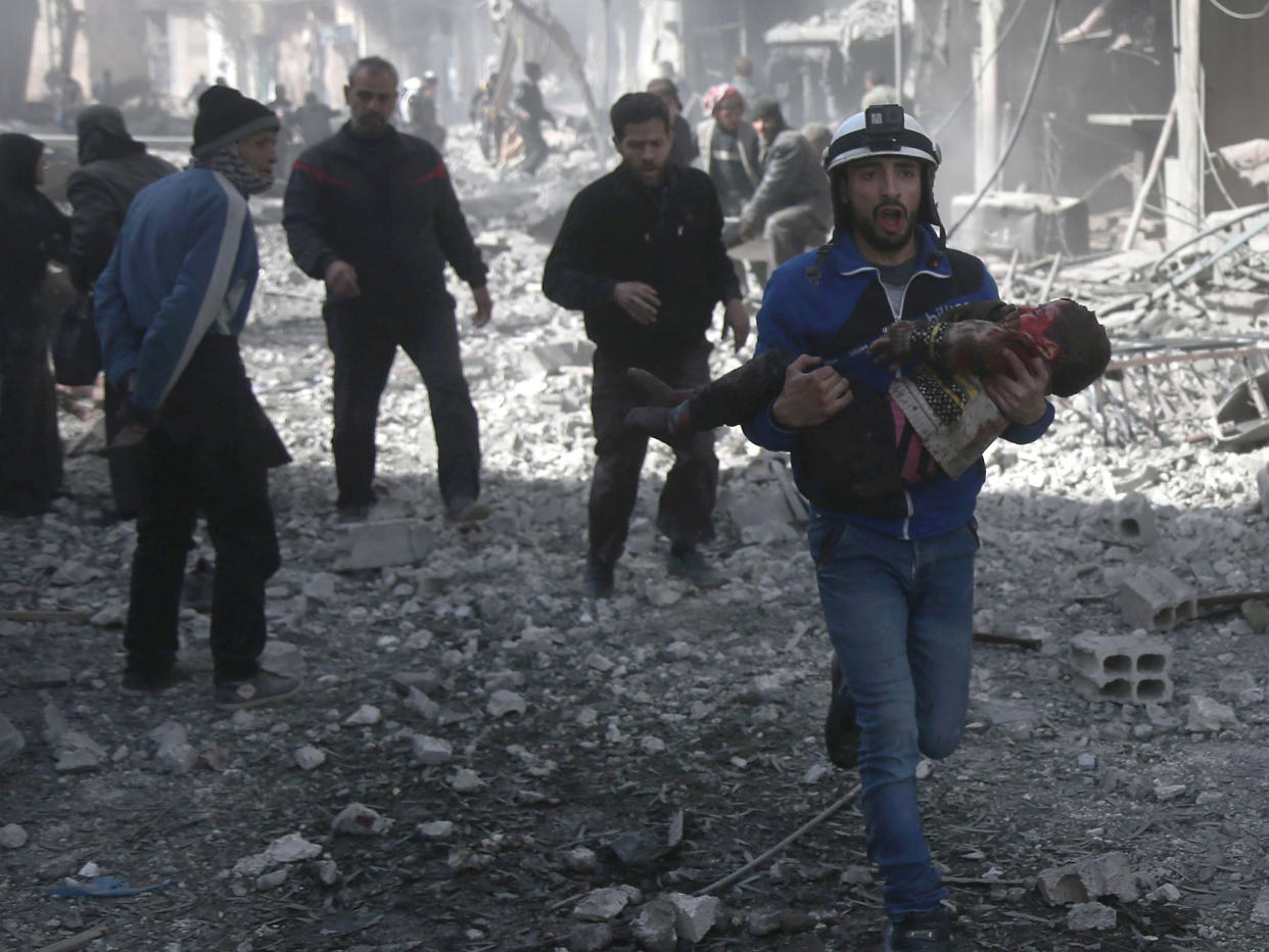 A Syrian civil defence member carries an injured child rescued from between the rubble of buildings following government bombing in the rebel-held town of Hamouria, in the besieged Eastern Ghouta region on the outskirts of the capital Damascus: ABDULMONAM EASSA/AFP/Getty Images