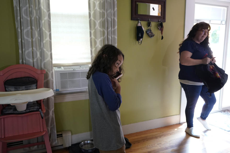 Gabriel Andrade-Cullen, 9, left, son of Allison Cullen, right, both of Brockton, Mass., speaks on the phone with his father Flavio Andrade Prado, from their home in Brockton, Thursday, July, 22, 2021. Prado, a Brazilian national, is being held by Immigration and Customs Enforcement, or ICE, at the Plymouth County House of Corrections. Cullen, a mother of two, says she and her children haven't been able to visit her husband since before the pandemic. (AP Photo/Steven Senne)