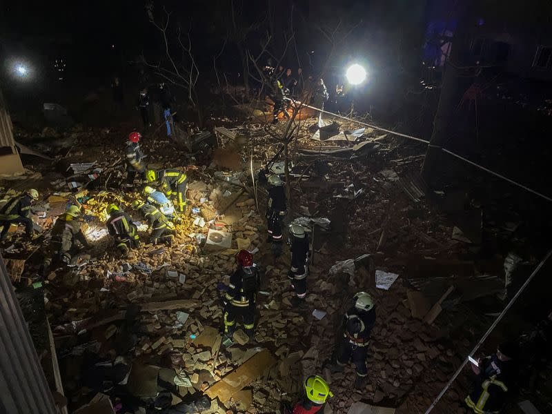 Ukrainian firefighters work at a site of an apartment building severely damaged by a Russian missile strike in Kharkiv